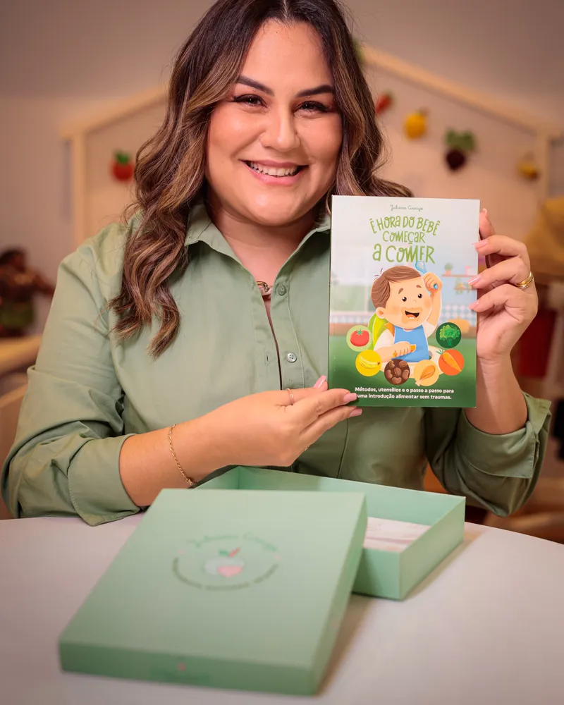 Juliana Araújo segurando o livro É hora do bebê começar a comer